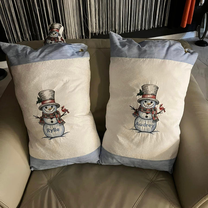 Two decorative pillows with machine embroidery snowmen on a chair.