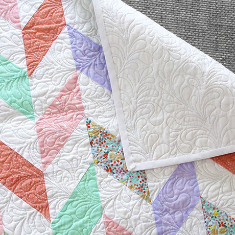 Machine embroidered edge-to-edge feather quilting design on a multi-colored fabric blanket.